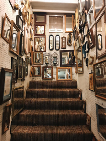 Assorted photo frames and mirrors pinned on a wall